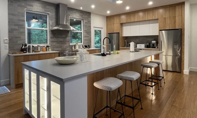 renovation-2017-10-agrandissement-quatre-saisons-16 2 Cuisine contemporaine avec grand îlot central, finitions en bois et électroménagers en acier inoxydable, réalisée par un entrepreneur général spécialisé en rénovations modernes.