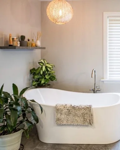 renovation-2018-11-19-renovations-generales-20 2 Salle de bain élégante avec baignoire autoportante, plantes décoratives et éclairage suspendu moderne, conçue par un entrepreneur général pour une ambiance apaisante.