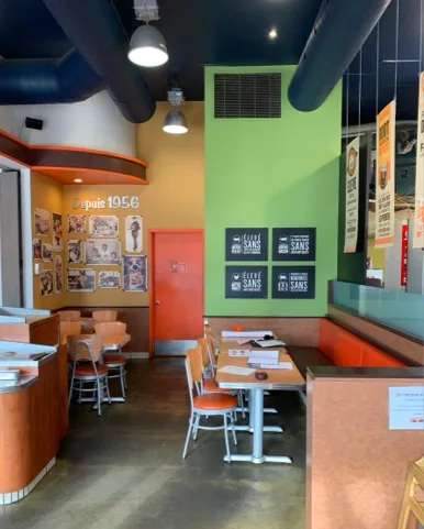 renovation-2018-11-19-renovations-generales-20 Intérieur d’un restaurant rétro avec des sièges orange et une décoration murale colorée, rénové par un entrepreneur général pour un style moderne et convivial.